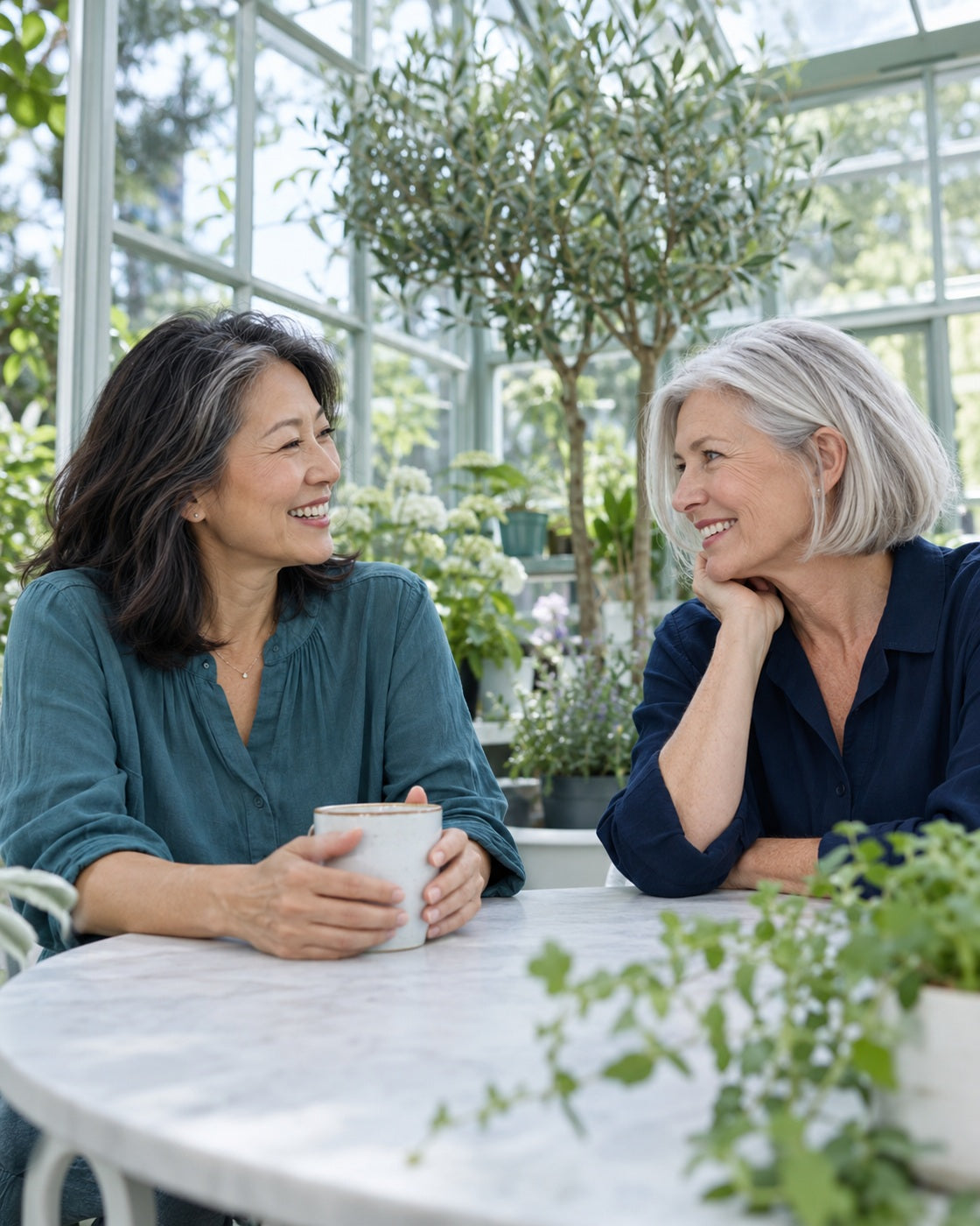 Two women sharing a relaxed conversation in a bright greenhouse